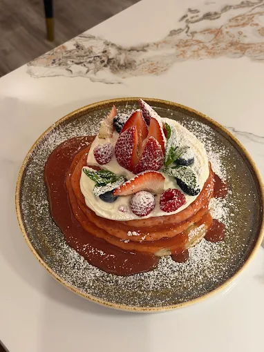Berry pancake stack with cream and powdered sugar